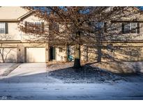 Tan two-story townhome with attached garage and snow-covered driveway at 7042 Tyler Ln, Indianapolis, IN 46217