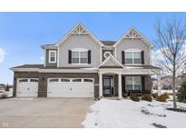 Two-story home with gray siding, brick accents, and a three-car garage at 9847 Gallop Ln, Fishers, IN 46040