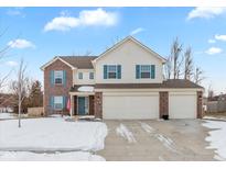 Two-story brick home with a three-car garage and snowy front yard at 12179 Country Side Dr, Cumberland, IN 46229