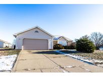 Beige house with attached garage, driveway, and landscaping; some snow on the ground at 7328 Woodside Dr, Avon, IN 46123