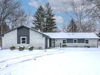 Charming ranch home with stone exterior and snowy front yard at 7107 Steinmeier Dr, Indianapolis, IN 46250
