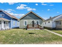 Charming single-story home with wood porch and green vinyl siding under a blue sky at 1503 N Grant Ave, Indianapolis, IN 46201