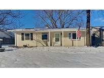 Ranch home with covered porch and American flag, snow covered yard at 227 Avalon Ln, Anderson, IN 46017