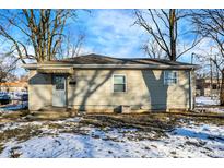 Tan house with gray door, steps, and small yard with patchy snow at 2319 N Rural St, Indianapolis, IN 46218