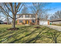 Charming two-story home featuring a brick facade, attached garage, and a well-manicured lawn at 9012 Colgate St, Indianapolis, IN 46268
