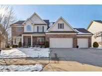 Charming two-story home featuring a brick and siding facade, a three-car garage, and a welcoming front porch at 14928 Declaration Dr, Westfield, IN 46074