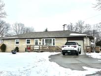Ranch home with a snow-covered yard, attached garage, and driveway at 4012 29Th St, Columbus, IN 47203