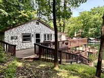 Charming stone home with a spacious deck overlooking the water and surrounding lush greenery at 7018 Drum Dr, Nineveh, IN 46164