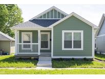 Charming green home with a inviting front porch and well-manicured landscaping at 1407 N Pershing Ave, Indianapolis, IN 46222