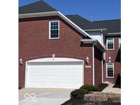 Exterior view of a red brick home featuring an attached two-car garage with a white door at 16375 Meadowlands Ln, Westfield, IN 46074