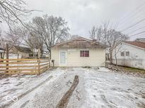 Small ranch home with wooden fence and snowy yard at 216 W 27Th St, Anderson, IN 46016