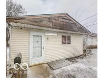 Modest home featuring vinyl siding, a white door, and a small window, presenting an opportunity for renovation at 216 W 27Th St, Anderson, IN 46016