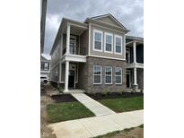 Inviting two-story home with brick accents, light beige siding and a cozy front porch with white columns at 525 Gilder Dr, Carmel, IN 46032