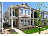 New construction townhome with brick and siding, manicured lawn, and sidewalk at 525 Gilder Dr, Carmel, IN 46032