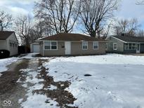 Cute ranch home with a snow-covered yard and attached garage at 2442 Asbury St, Indianapolis, IN 46203