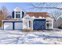 Charming two-story house with a blue exterior and a snow covered front yard at 7358 Benoit Dr, Indianapolis, IN 46214