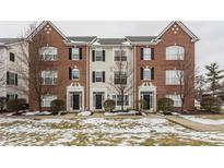 Three-unit townhome building with brick and siding, featuring landscaping and a snowy lawn at 2342 The Springs Dr, Indianapolis, IN 46260