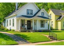 Charming two-story home featuring a covered porch and beautifully landscaped front yard and black trimmed windows at 3816 Rookwood Ave, Indianapolis, IN 46208