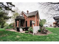 Charming red brick home featuring a cozy patio, lush green lawn, and delightful outdoor seating at 301 Lowry St, Jamestown, IN 46147