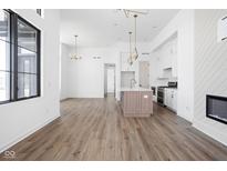 Open-concept living space featuring wood floors, pendant lighting, and seamless connection between living, dining, and kitchen at 1674 Solebar Way, Westfield, IN 46074