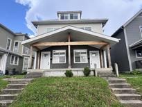 Charming duplex with a covered front porch and a well-maintained lawn at 2033 Carrollton Ave, Indianapolis, IN 46202