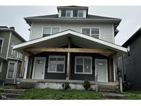 Charming two-story duplex with a covered porch, showcasing its inviting curb appeal and design at 2033 Carrollton Ave, Indianapolis, IN 46202