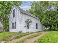 White house with a gravel driveway, surrounded by lush green trees at 230 W 22Nd St, Anderson, IN 46016