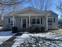 Gray house with white trim, covered porch, and landscaping; located on a snow-covered lot at 409 E Ulen Dr, Lebanon, IN 46052