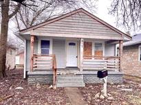 A compact single-story home featuring a covered front porch, wood siding, and a peaked roofline at 817 N Linwood Ave, Indianapolis, IN 46201