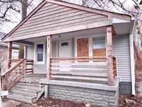 A compact single-story home featuring a covered front porch, wood siding, and a peaked roofline at 817 N Linwood Ave, Indianapolis, IN 46201