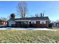 Brick ranch home with covered porch, attached garage, and landscaped lawn at 129 E Stop 13 Rd, Indianapolis, IN 46227