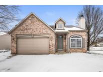 Charming brick home featuring an attached garage and snow covered yard in a quiet neighborhood at 3138 River Shore Pl, Indianapolis, IN 46208