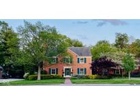 Charming brick home featuring lush landscaping, a welcoming entrance and classic shuttered windows at 6551 Forrest Commons Blvd, Indianapolis, IN 46277