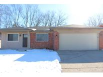 Brick ranch home with attached garage and snow-covered front yard at 9903 E 17Th St, Indianapolis, IN 46229