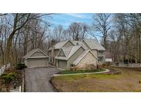 Stunning home features a unique roofline, stone accents, three car garage, and mature trees at 14519 Cherry Tree Rd, Carmel, IN 46033