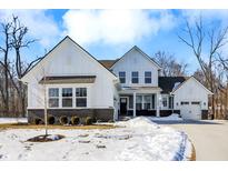 Newly built home with three car garage, neutral siding, dark brick foundation, and fresh snowfall at 16258 Perrault Ct, Fishers, IN 46040