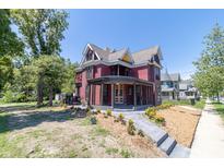 Beautiful red Victorian home with wrap-around porch and landscaped yard at 404 N State St, Greenfield, IN 46140