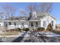 Charming white farmhouse with wrap-around porch and mature trees at 4462 S Morgantown Rd, Greenwood, IN 46143