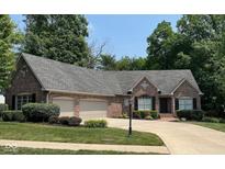 Charming brick home with a well-manicured lawn, two-car garage, and lush landscaping at 11253 Loch Raven Blvd, Fishers, IN 46037