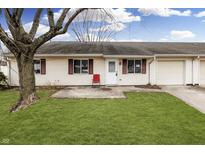 Tan house with a red chair on the patio, a single-car garage, and a yard at 3400 Winchester Dr, Indianapolis, IN 46227