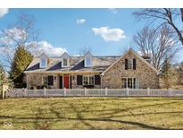 Charming stone home featuring a bright red door, dormer windows and a white picket fence at 7837 Dean Rd, Indianapolis, IN 46240