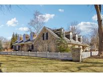 Beautiful stone home with dormer windows and a white picket fence, set on a lush green lawn at 7837 Dean Rd, Indianapolis, IN 46240
