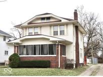Charming two-story home featuring a brick foundation, enclosed front porch, and a well-maintained lawn at 917 E 34Th St, Indianapolis, IN 46205