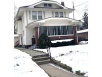 Two-story house with a screened porch and snowy front yard at 917 E 34Th St, Indianapolis, IN 46205