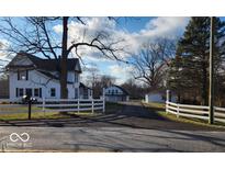 Charming white farmhouse with black shutters, set back from the road behind a white fence at 5420 Mcfarland Rd, Indianapolis, IN 46227