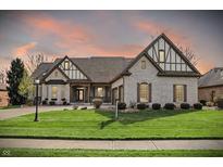 Beautiful, light brick home featuring a manicured lawn and Tudor-style architectural accents at 14565 Geist Ridge Dr, Fishers, IN 46040