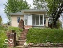 Quaint single-story home featuring a screened front porch, beige siding, and a landscaped front yard at 252 Ringwood Way, Anderson, IN 46013