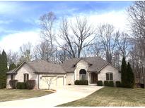Charming single-story brick home featuring an attached two-car garage and a well-manicured lawn, set against a beautiful wooded backdrop at 4696 E County Road 100 S, Avon, IN 46123