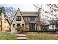Tudor style home with stone exterior, landscaped lawn, and a sunroom at 5733 Carrollton Ave, Indianapolis, IN 46220