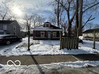 Brick home with front porch, snowy yard, and mature trees at 1459 W 33Rd St, Indianapolis, IN 46208